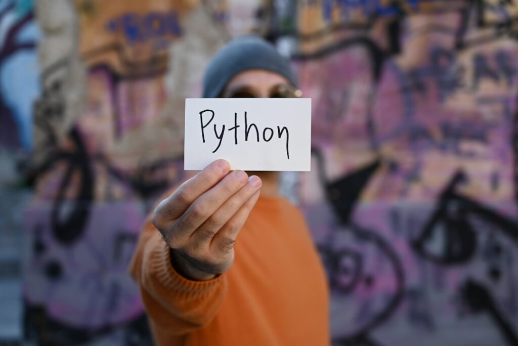 ChemiCloud 한국 워드프레스 호스팅 SSH Python 환경변수 - a man holding up a piece of paper with the word python written on it